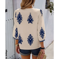 Back view of cream-colored embroidered casual vacation blouse with navy blue embroidered floral patterns on sleeves and back