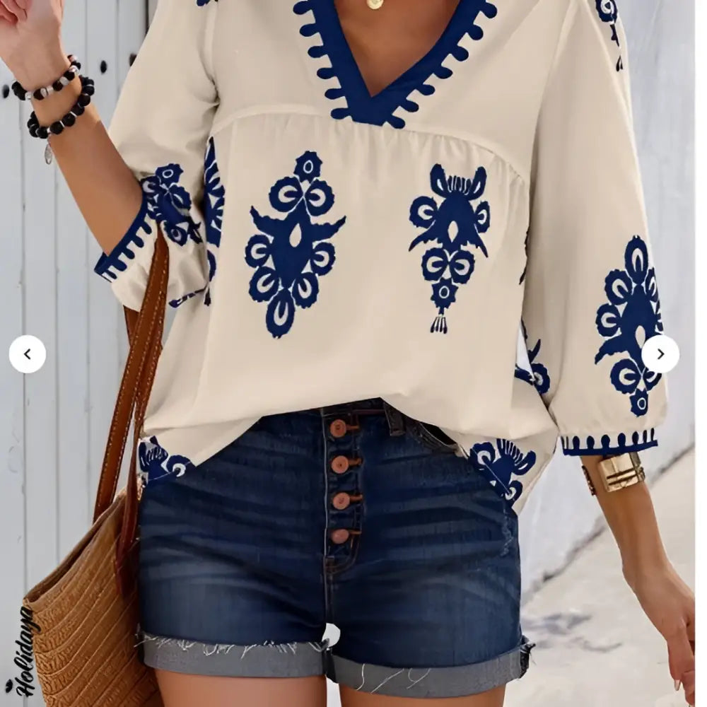 Cream-colored casual vacation embroidered blouse with navy blue floral patterns and decorative trim on v-neckline and sleeves