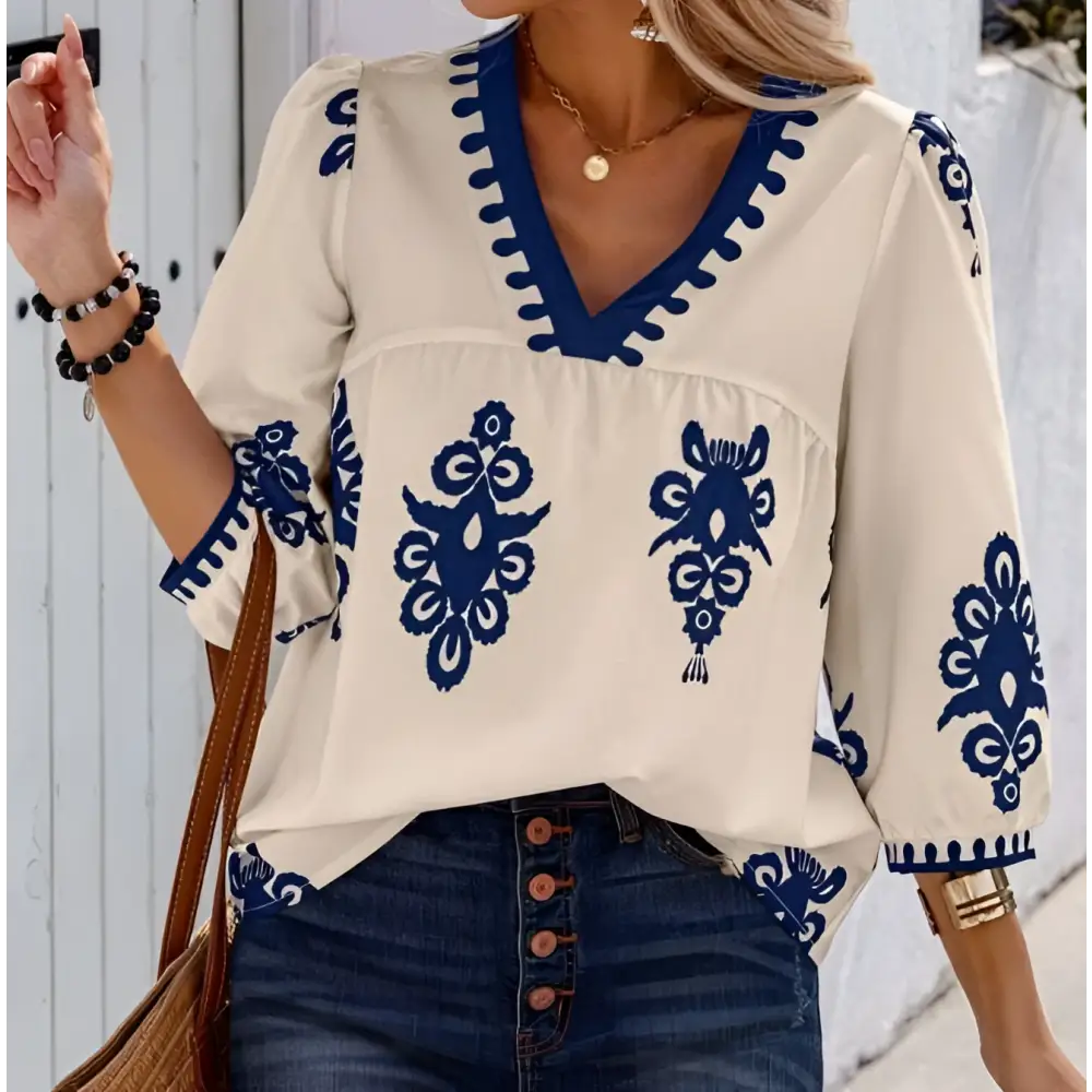 Beige embroidered casual vacation blouse with navy blue floral patterns and decorative trim for cream-colored casual wear