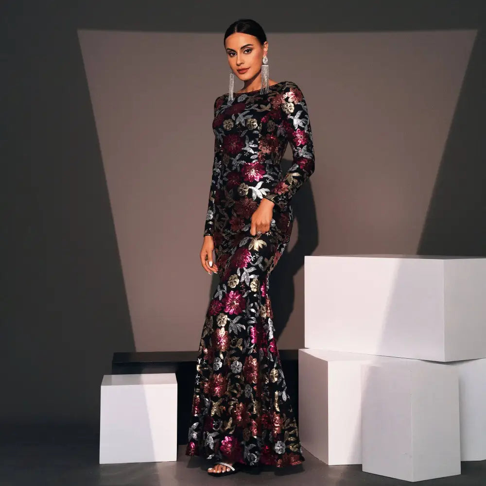 A black long-sleeved evening gown with shimmering burgundy and gold embroidered floral details floor-length