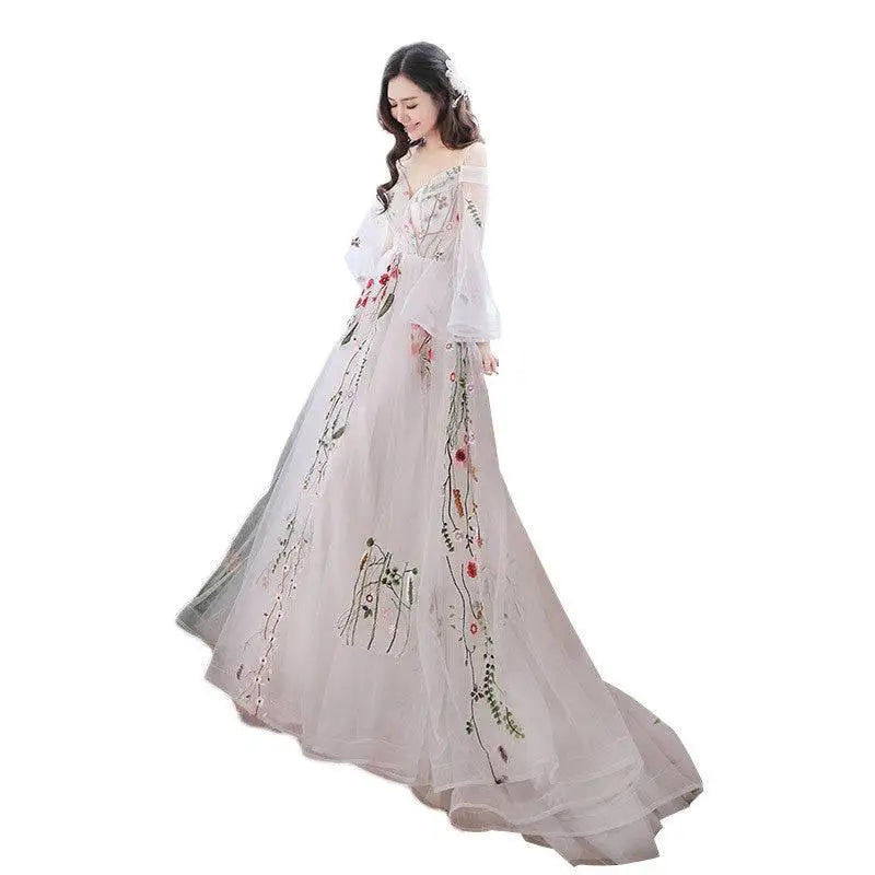 A flowing off-the-shoulder retro bridal gown in sheer pale gray tulle featuring delicate floral embroidery with red and green accents