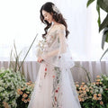 A delicate off-the-shoulder retro bridal gown in gray tulle with intricate floral embroidery and sheer flowing sleeves