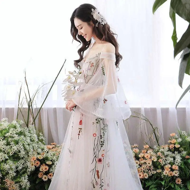 A delicate off-the-shoulder retro bridal gown in gray tulle with intricate floral embroidery and sheer flowing sleeves