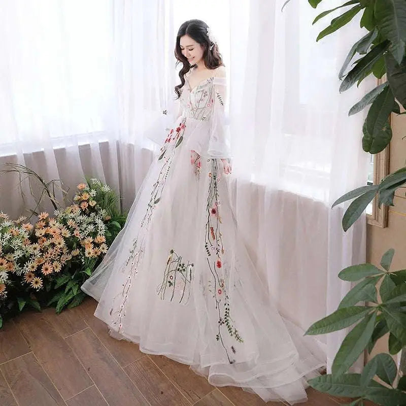 A flowing white tulle off-the-shoulder retro bridal gown with delicate red pink and green floral embroidery