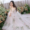 A flowing off-the-shoulder retro bridal gown in gray tulle with delicate floral embroidery in pink and green hues