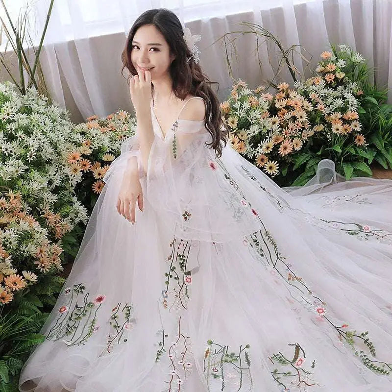 A flowing off-the-shoulder retro bridal gown in gray tulle with delicate floral embroidery in pink and green hues
