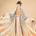 A woman wears embroidered han chinese clothing in pastel green and cream with delicate floral embroidery for summer use