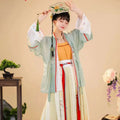 A woman wears light green embroidered han Chinese clothing with floral embroidery and red trim over an orange top