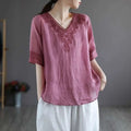 A soft pink cotton linen blouse with intricate dark red embroidery on v-neckline and sleeve cuffs fashion retro cotton