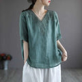 A soft teal cotton linen blouse with embroidered pink fashion retro detailing on the v-neckline and sleeve cuffs