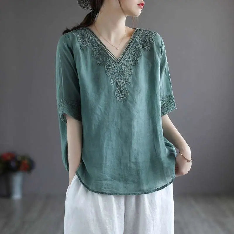 A soft teal cotton linen blouse with embroidered pink fashion retro detailing on the v-neckline and sleeve cuffs