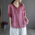A soft pink cotton linen blouse with intricate dark red embroidery on the v-neckline and sleeve cuffs fashion retro cotton