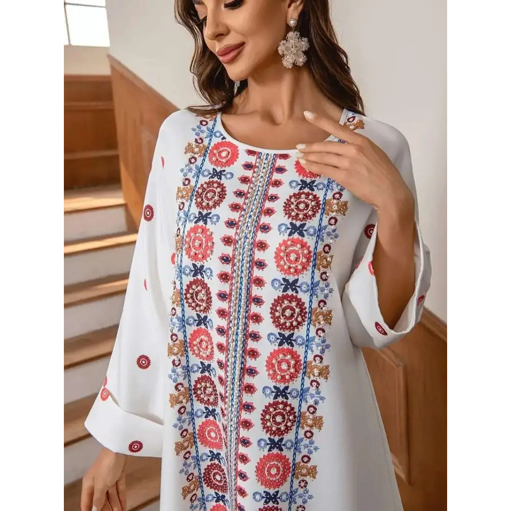 White embroidered rhinestone bead long sleeve maxi dress with vibrant red blue and gold floral print patterns