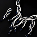 A silver-toned zircon jewelry set necklace with flowing branches adorned with deep blue sapphires and emerald green crystal