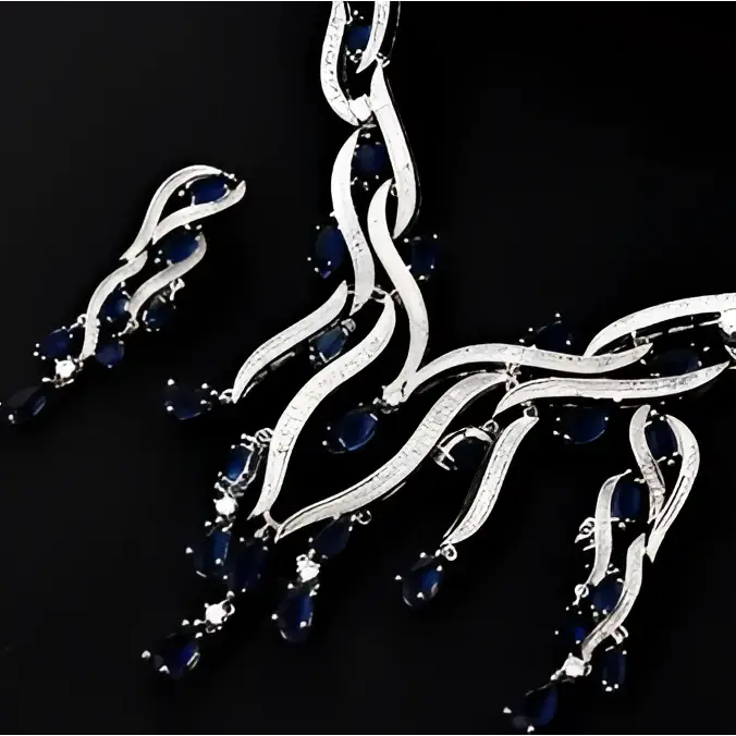 A silver-toned zircon jewelry set necklace with flowing branches adorned with deep blue sapphires and emerald green crystal