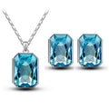A pair of silver-toned earrings and matching crystal necklace pendant featuring radiant turquoise emerald green crystal stones