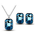 A sparkling royal blue emerald-cut crystal necklace pendant with matching stud earrings set in silver-toned metal