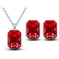 Emerald green crystal necklace pendant and matching earrings set with red rectangular gemstones in silver-toned metal