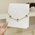 Emerald pearl flowers bracelet with delicate gold chain featuring three floral motifs with emerald gems and pearls