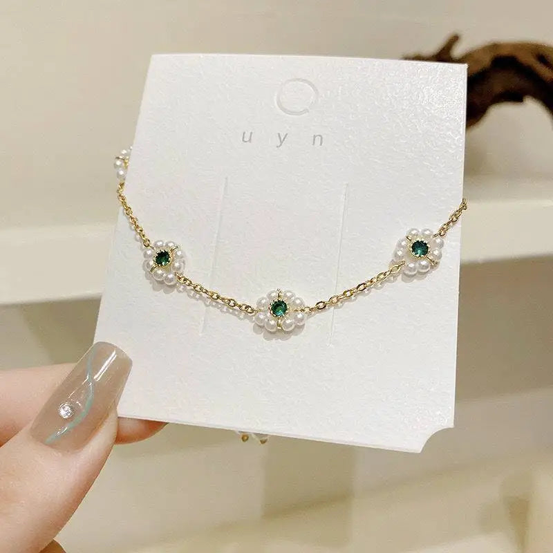 Emerald pearl flowers bracelet with delicate gold chain featuring three floral motifs with emerald gems and pearls