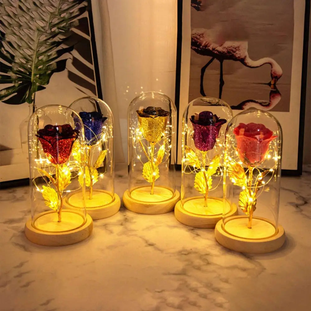 A collection of five eternal rose led illuminated preserved roses with golden stems in elegant glass dome romantic gift