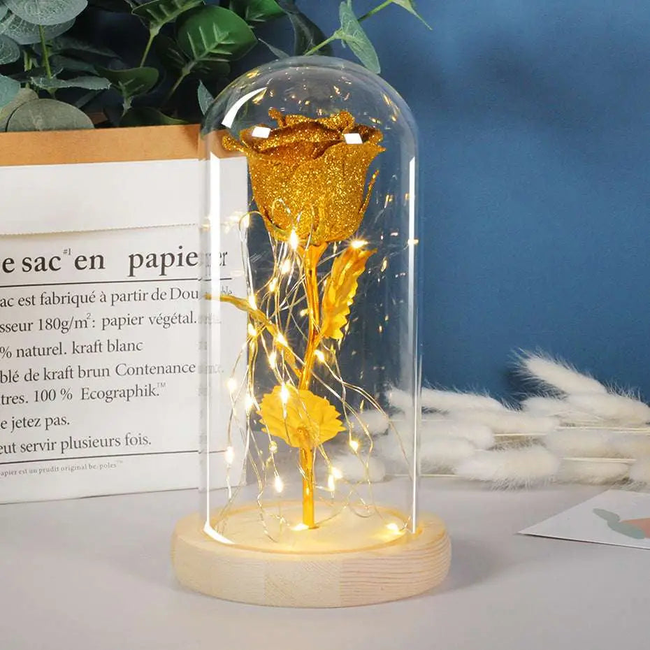 Eternal rose led light featuring a golden glitter rose in an elegant glass dome on a light wood base for a romantic gift