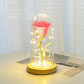 A pink preserved eternal rose led light with golden stem in an elegant glass dome and wooden base romantic gift set