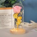 A pink glittery eternal rose led with golden leaves inside an elegant glass dome with fairy lights romantic gift