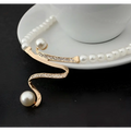 A delicate gold-toned european fashion diamond crystal pearl jewelry set necklace with swirling design and two white pearls