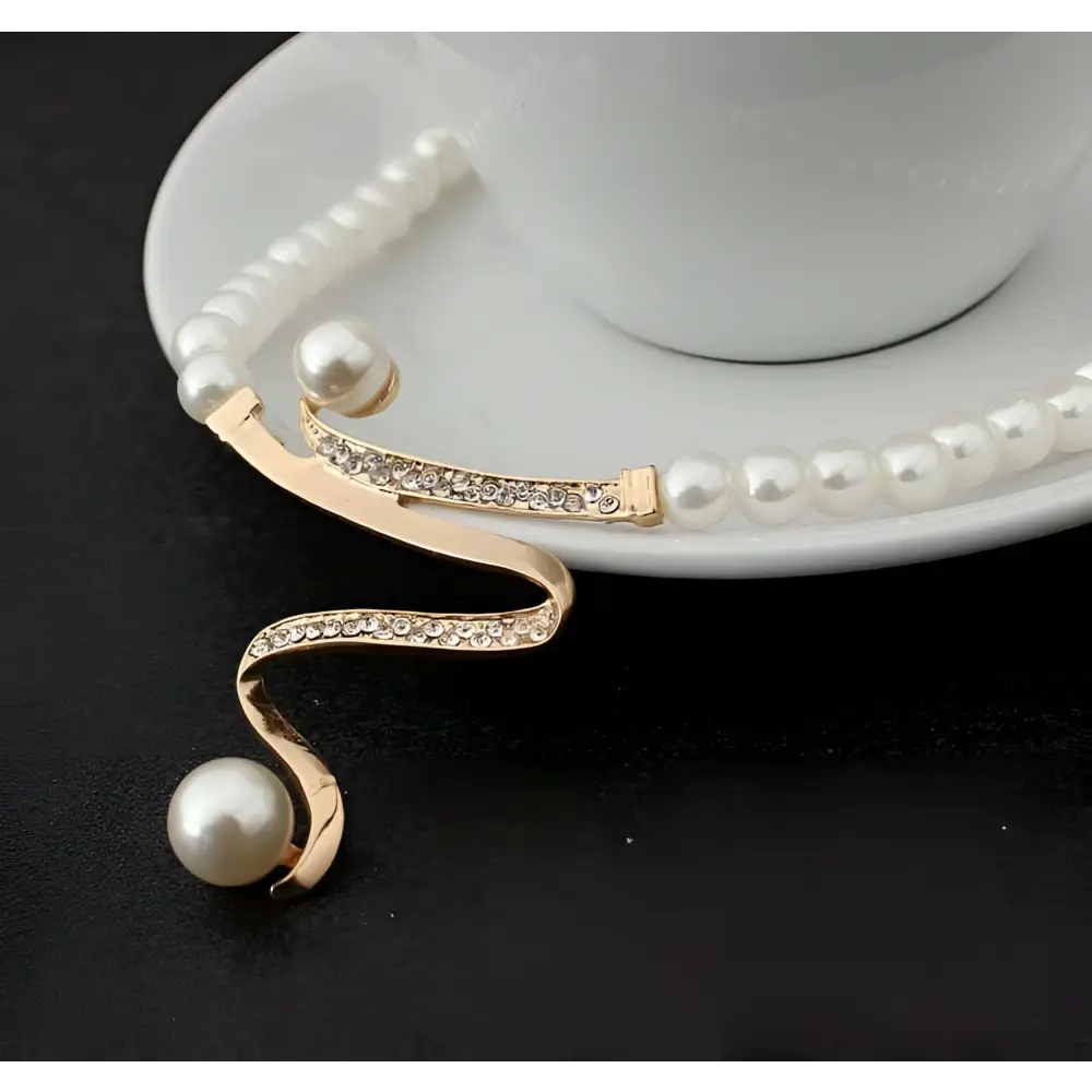 A delicate gold-toned european fashion diamond crystal pearl jewelry set necklace with swirling design and two white pearls