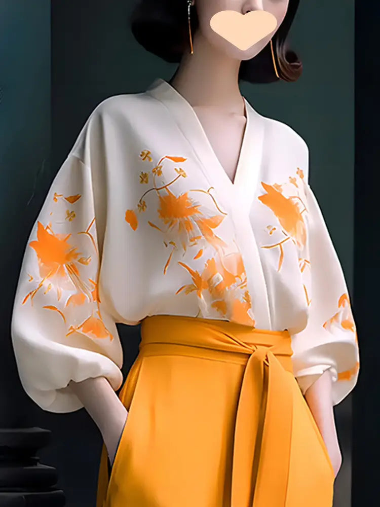 a flowing off-white silk blouse with delicate orange floral embroidery and voluminous sleeves designed as slimming wear flab hiding shirt