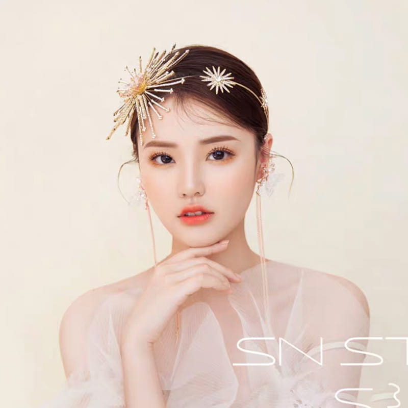 A delicate gold-toned starburst bridal rhinestone headband featuring sparkling rhinestones and fine metallic filigree as an elegant hair accessory.