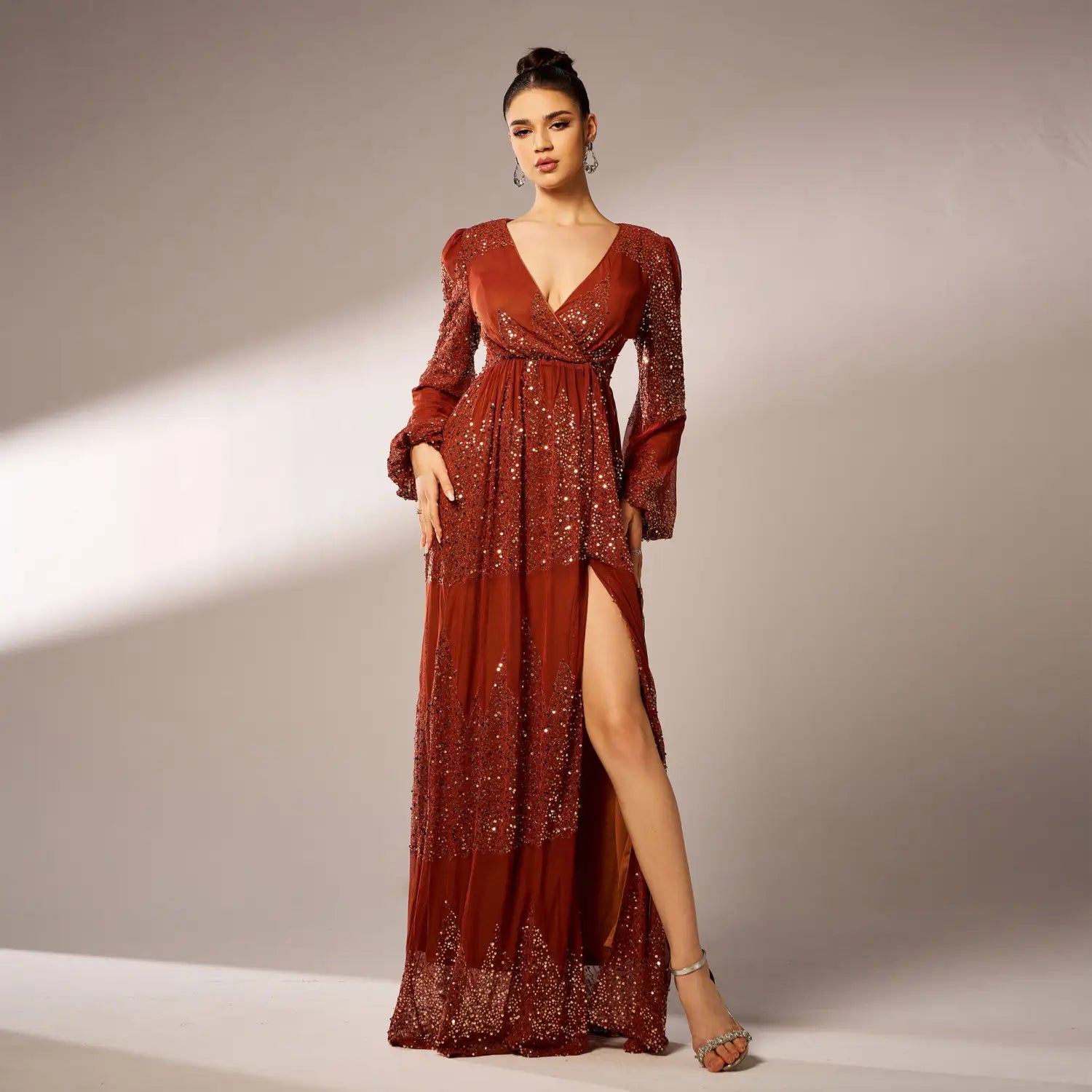 A shimmering rust bell sleeve sexy long sequined evening dress with long flared sleeves and a high slit adorned with sparkling sequins across the bodice and skirt.