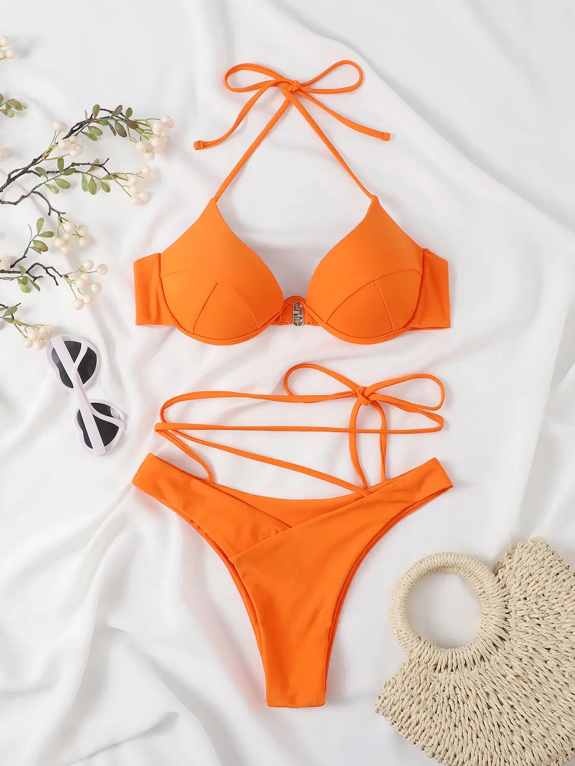 Bright orange split bikini set featuring a halter top with tied straps and a central metallic clasp paired with high-cut crisscross tied bottoms.