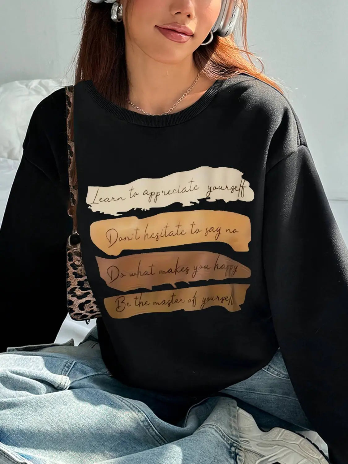 Black oversized long sleeve sweatshirt with motivational quotes printed in beige and gold on horizontal stripes designed for daily wear as a solid colour garment.