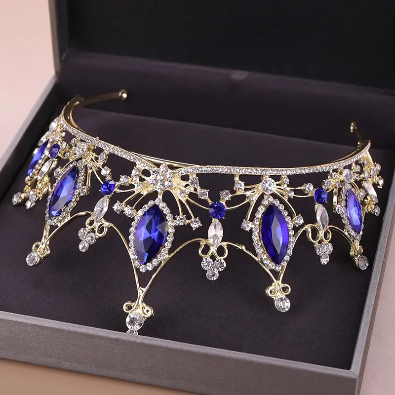 a gold-toned crystal crown bride adorned with deep blue and clear crystals in an ornate symmetrical design, serving as a bride golden headband