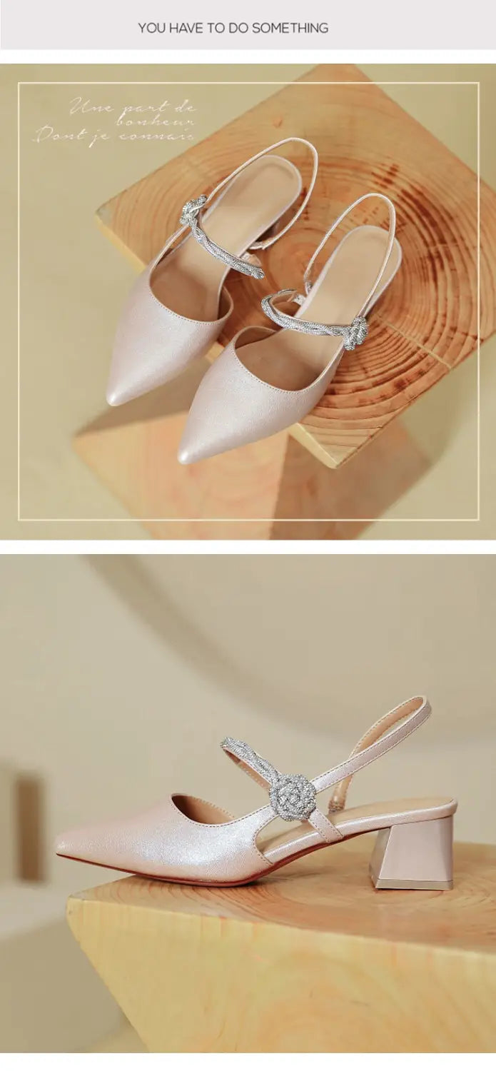 Cream-colored satin pointed toe high heels featuring a crystal-embellished strap and a chunky heel suitable for elegant occasions.