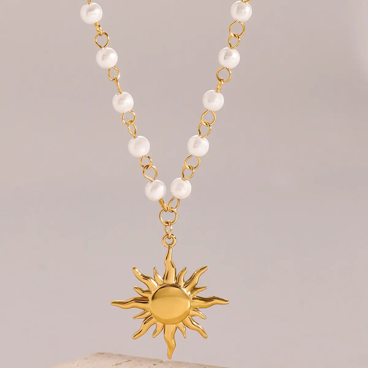 stainless steel pearl necklace with gold sun pendant featuring a chain of white pearls and gold links
