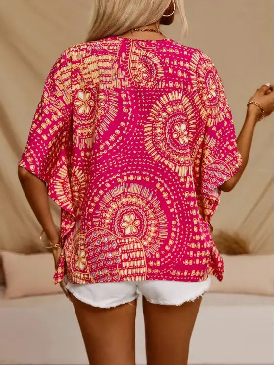 Vibrant pink bohemian vacation style batwing top with intricate orange and white paisley patterns and flowing style batwing sleeves.
