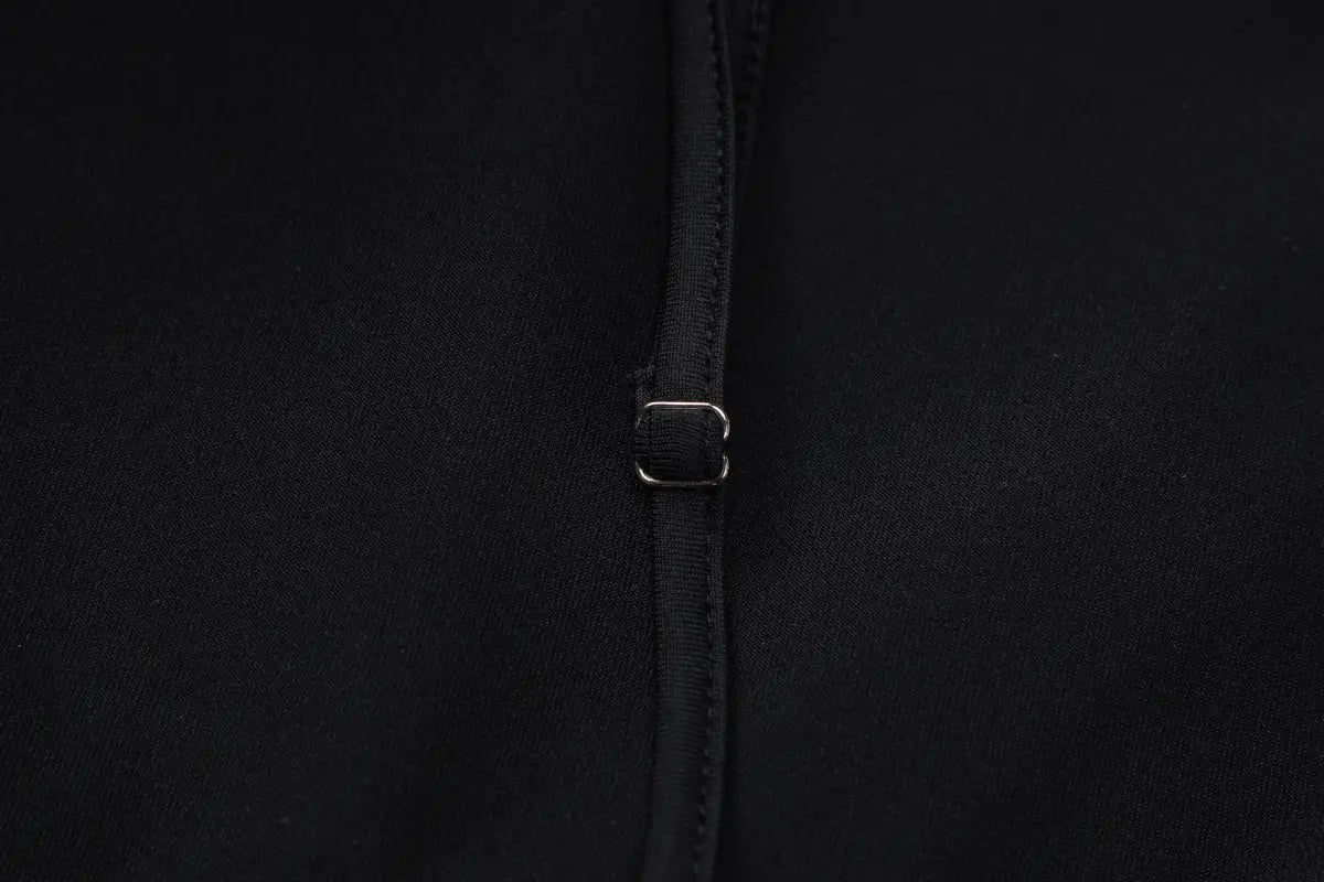 Black fabric with a silver-toned metal buckle and zipper pull detail on a sexy hot girl long sleeve dress featuring a hollow out design.