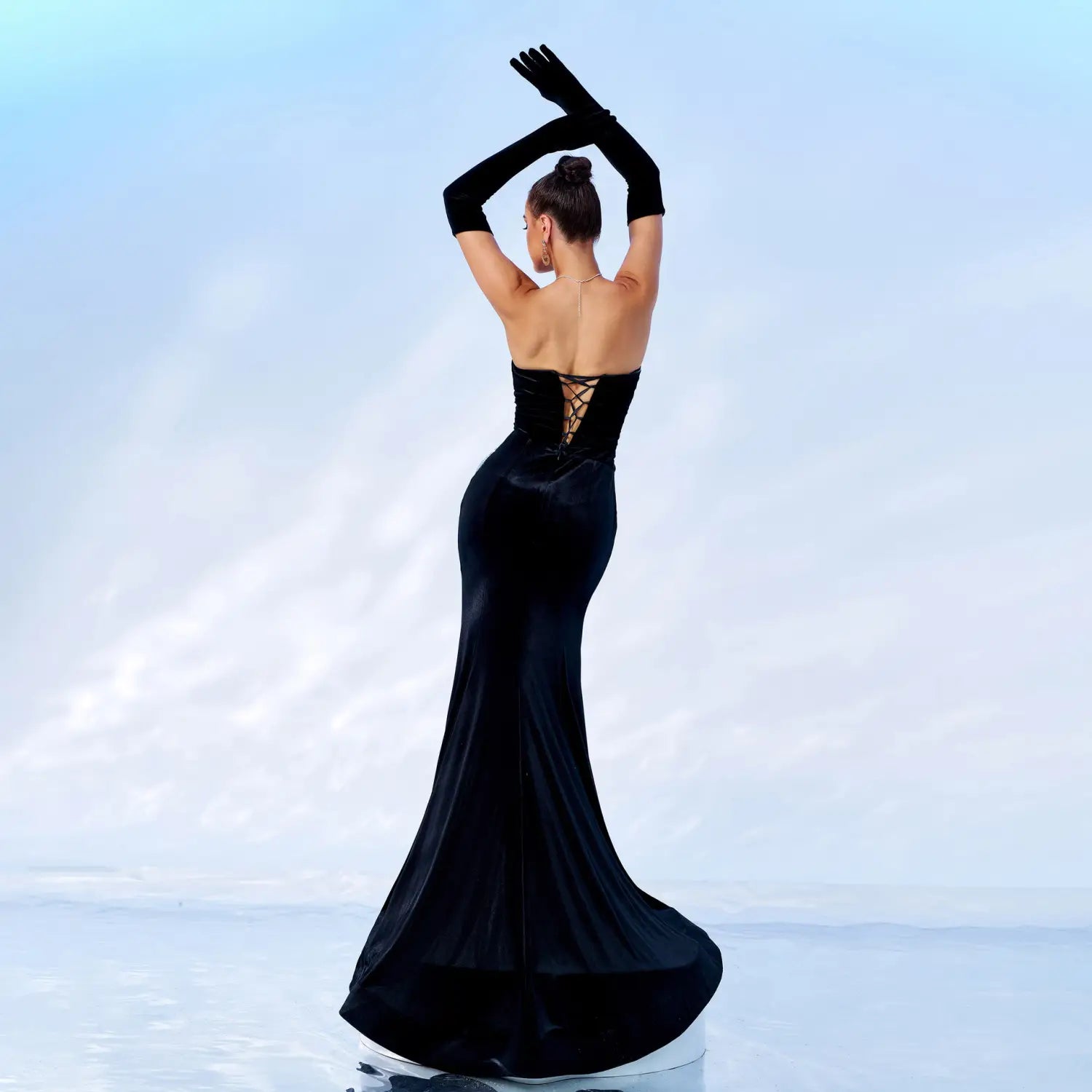 A sleek black velvet mermaid gown with a corseted back and long gloves featuring a chest wrap hip high design.