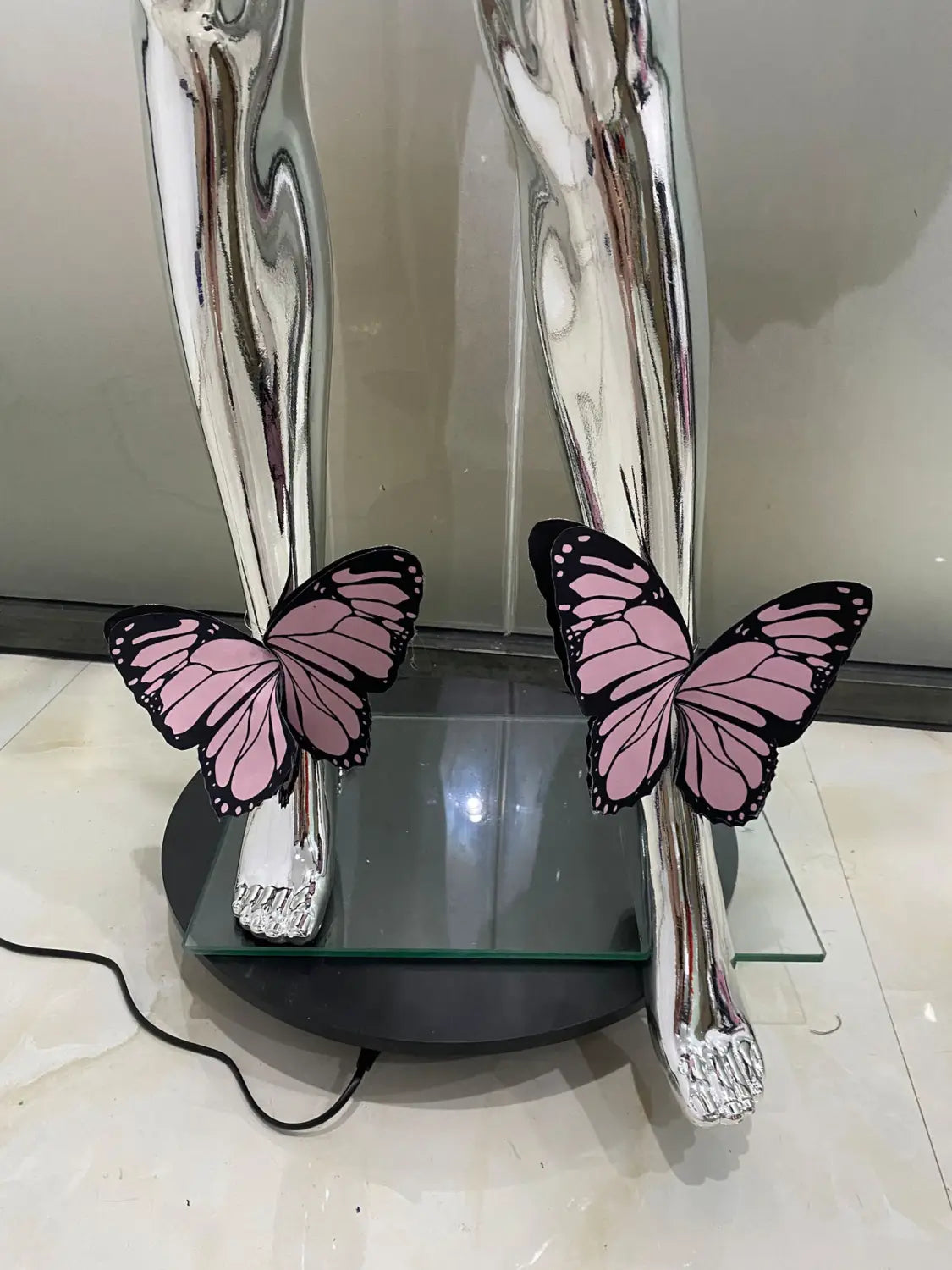 Shiny silver metallic sculpture with two pink and black butterfly ornaments perched on stylized legs complements the sequin butterfly latin dance skirt dress made with net yarn stretch for optimal movement.