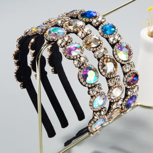 A baroque colorful headband featuring a multi-layered iridescent rhinestone design with a black comb base and gold-toned metal accents.