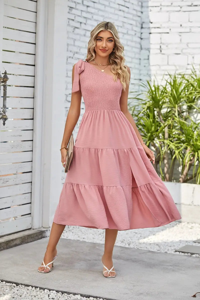 a soft pink tiered midi dress with a smocked bodice and delicate shoulder bows featuring a pleated layered hem and a layered hem split design ideal as a hem split dress