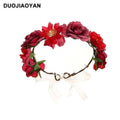 A fabric colorful rose flower garland hair accessory with red artificial roses, green leaves, and a white ribbon bow