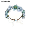 A delicate fabric colorful rose flower garland hair accessory with blue blooms and braided brown vine tied in a bow