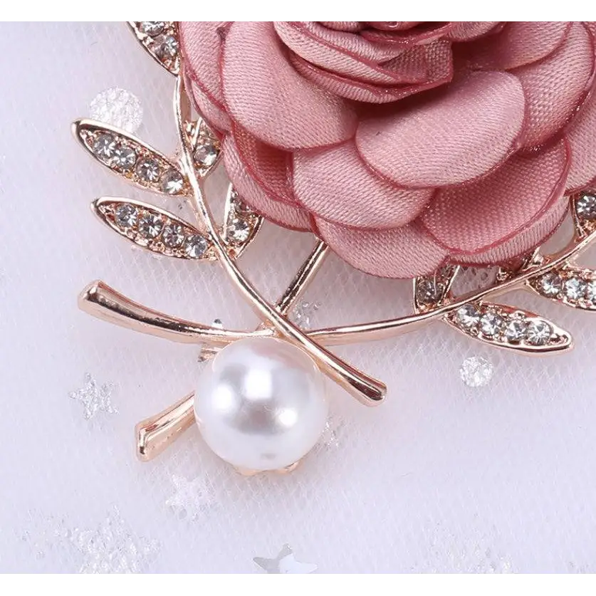 A delicate fabric flower lady temperamental pin featuring a pink satin rose and rhinestone floral brooch set accents