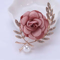 Delicate fabric flower lady temperamental pin with soft pink satin rose, gold metal leaves, clear crystals, and pearl drop