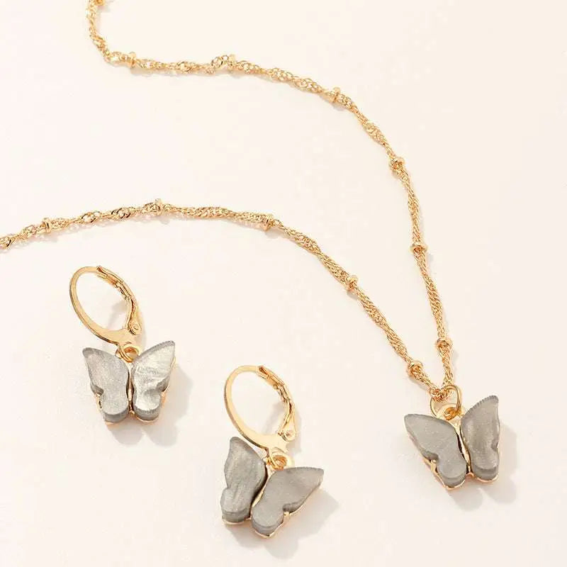 Fashion resin butterfly necklace and matching gold hoop earrings with gold-toned setting and translucent gray wings