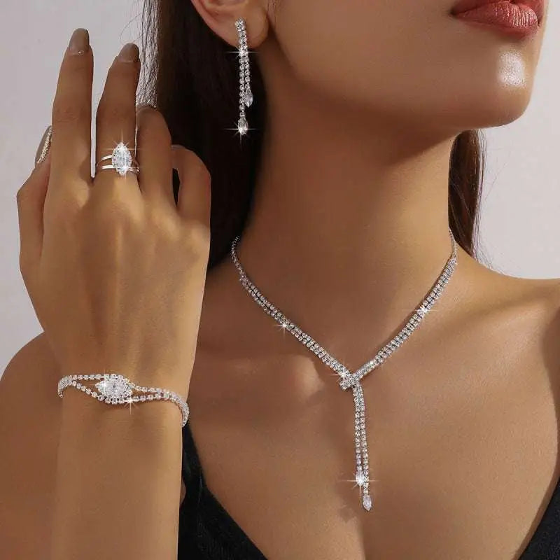 A silver-toned silver rhinestone necklace with v-shaped design and teardrop pendant in a necklace earring bracelet set